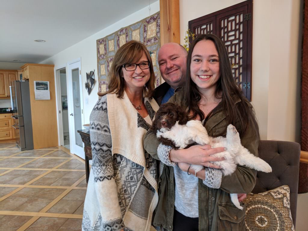 Family with daughter holding their new labradoodle puppy