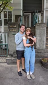 Chocolate phantom Australian labradoodle being held by a young couple outside their condo